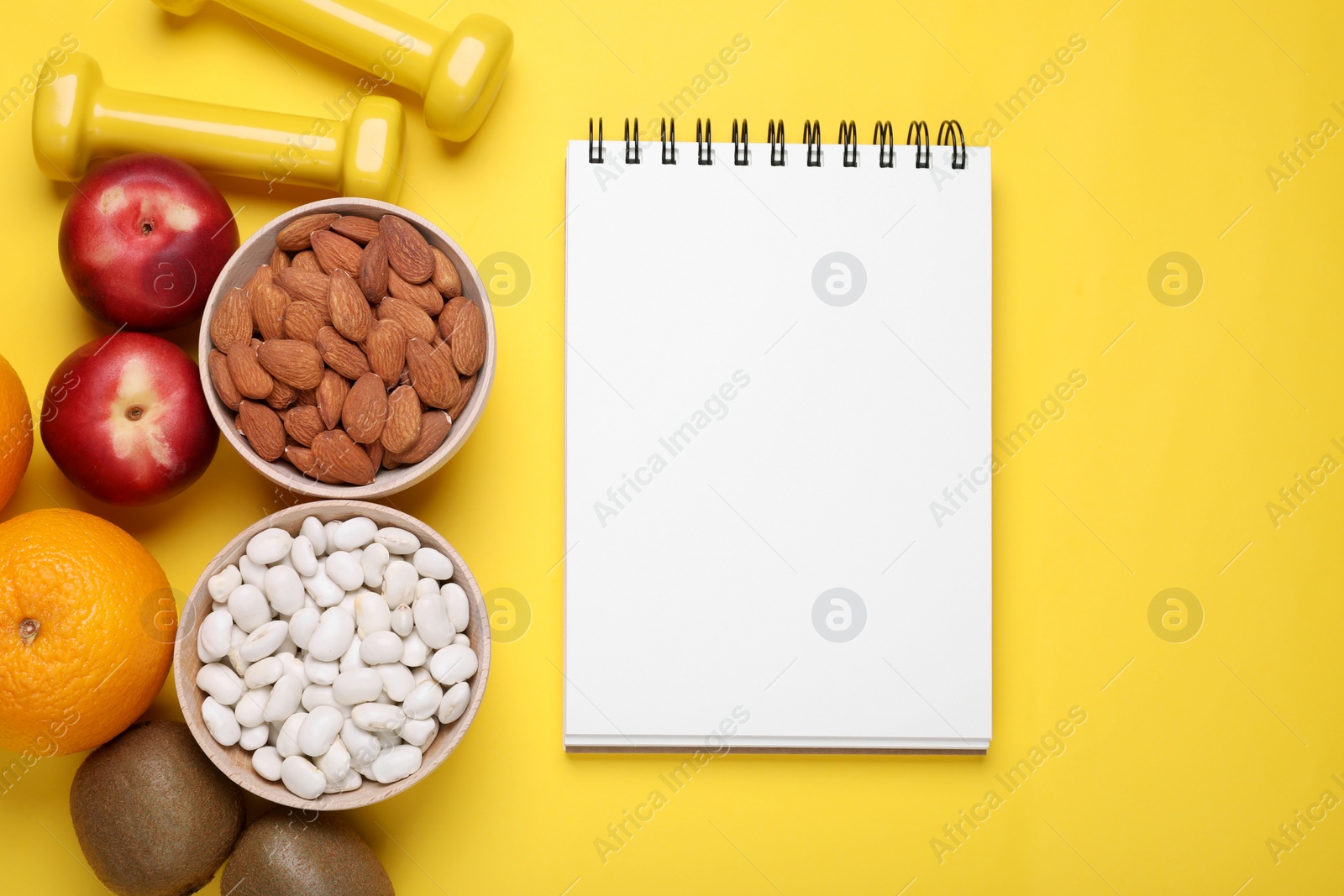 Photo of Notebook, fresh fruits and almonds on yellow background, flat lay. Low glycemic index diet