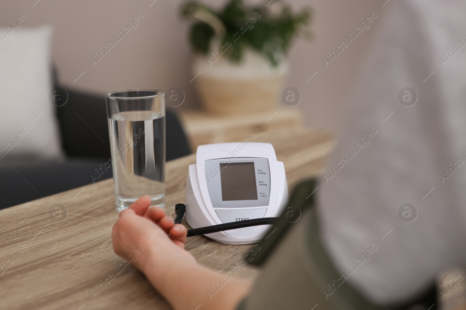 Photo of Woman checking blood pressure at wooden table indoors, closeup