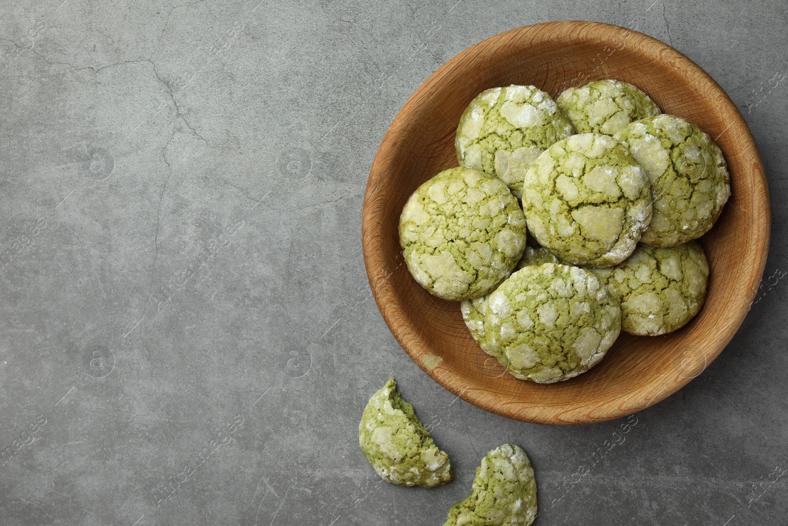 Photo of Bowl with tasty matcha cookies on grey textured table, flat lay. Space for text