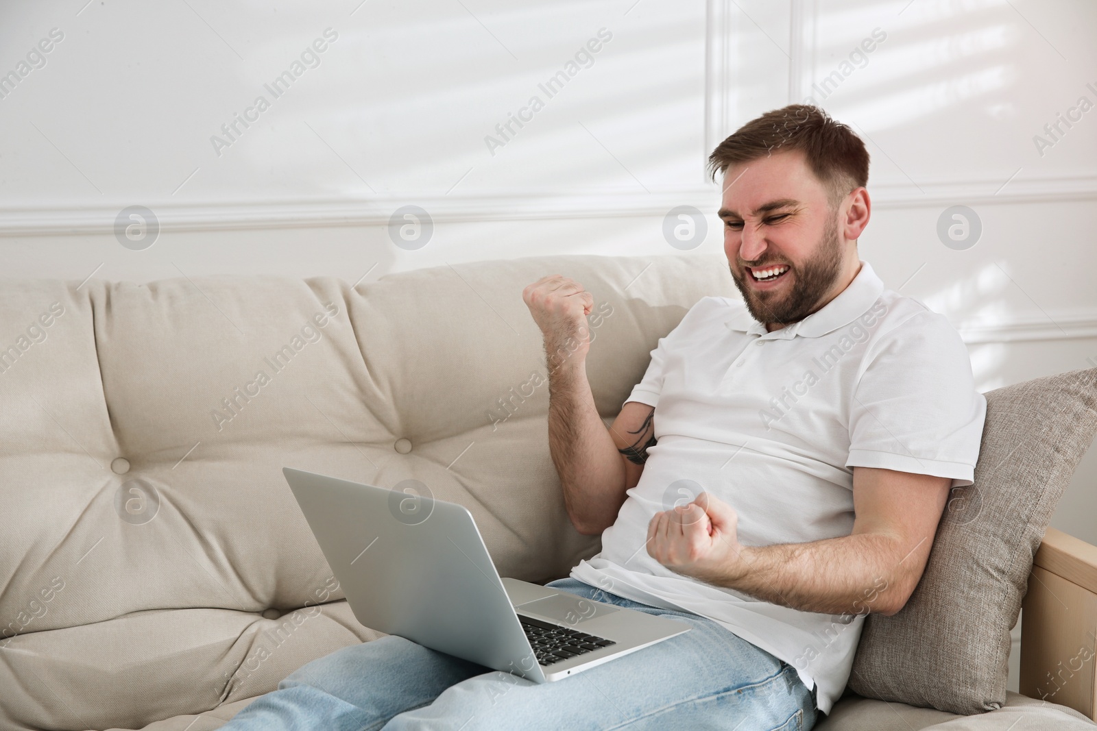 Photo of Emotional man participating in online auction using laptop at home