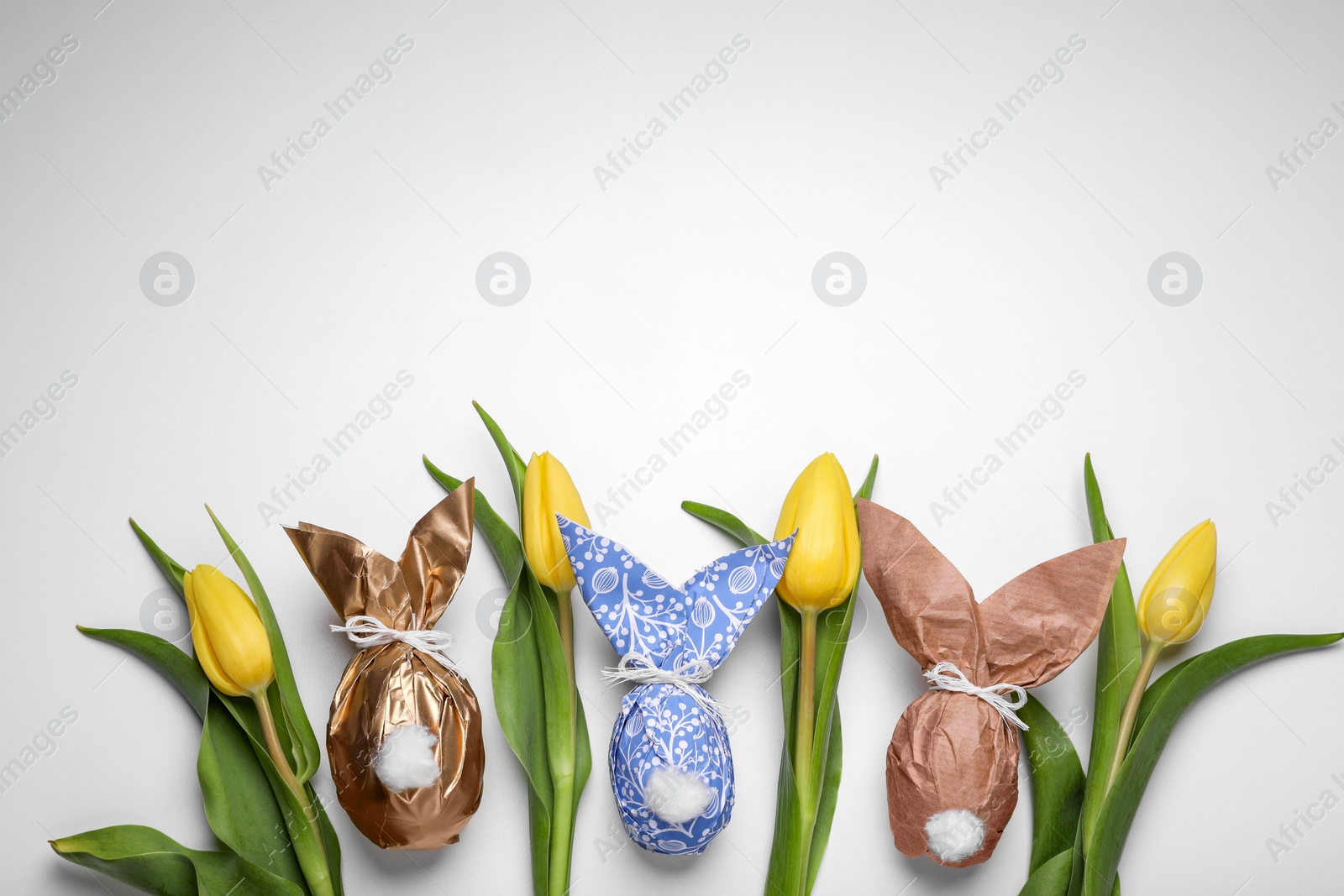 Photo of Flat lay composition with Easter bunnies made of paper and eggs on white background. Space for text