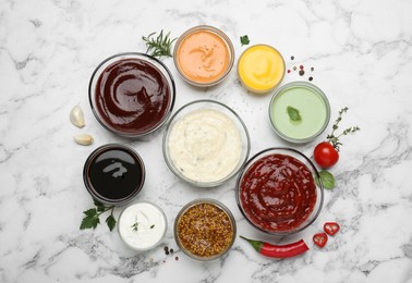 Photo of Many different sauces and herbs on white marble table