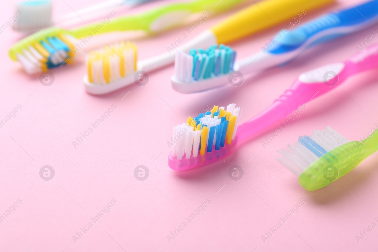 Photo of Many different toothbrushes on pink background, closeup. Space for text