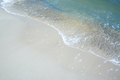 Photo of Beautiful sea waves on sandy beach, closeup