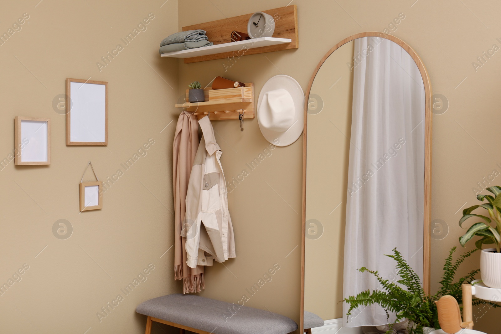 Photo of Hallway interior with stylish furniture, accessories and wooden hanger for keys on beige wall