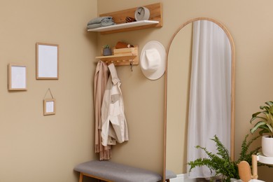 Hallway interior with stylish furniture, accessories and wooden hanger for keys on beige wall