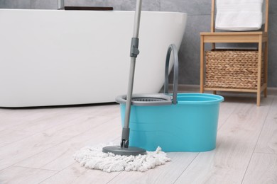 Photo of Mop and plastic bucket in bathroom. Cleaning floor