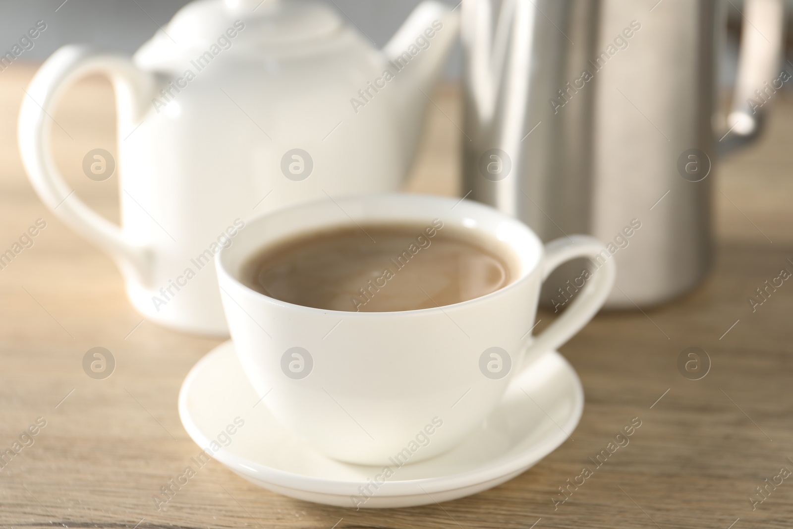 Photo of Aromatic tea with milk in cup on wooden table, closeup