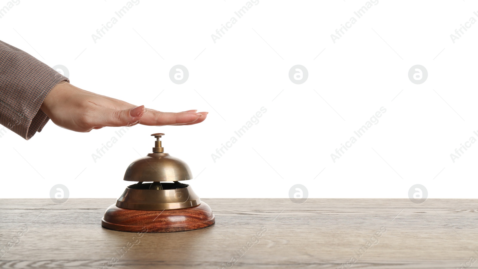 Photo of Woman ringing hotel service bell at wooden table