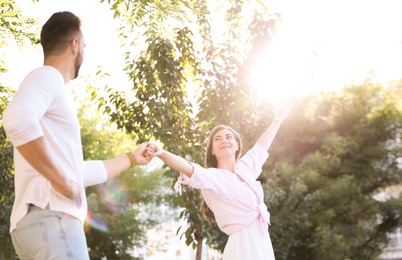 Lovely young couple dancing together in park on sunny day