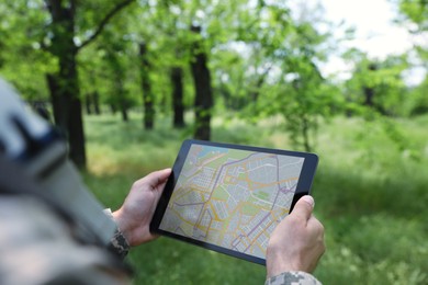 Soldier using tablet in forest, closeup view