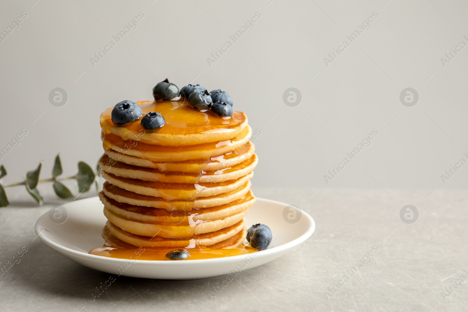 Photo of Plate with pancakes and berries on grey background