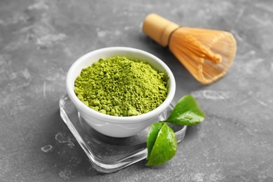 Photo of Matcha tea in bowl, whisk and green leaves on table