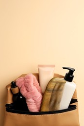 Preparation for spa. Compact toiletry bag with different cosmetic products on beige background, top view. Space for text