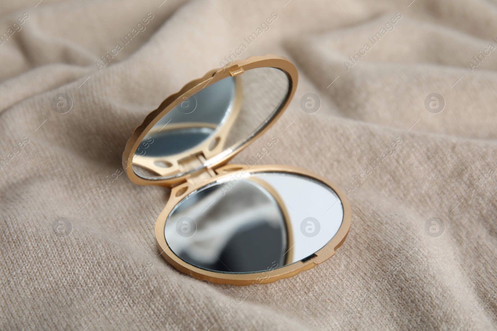 Photo of Stylish cosmetic pocket mirror on brown fabric