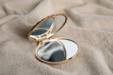 Stylish cosmetic pocket mirror on brown fabric