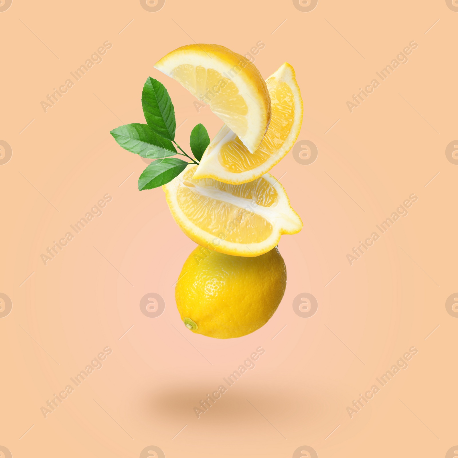 Image of Cut and whole fresh lemons with green leaves falling on pale coral background