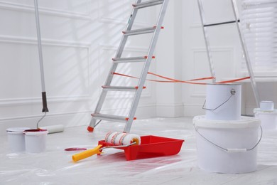 Photo of Metal stepladder, buckets of paint and renovation tools indoors