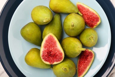 Photo of Cut and whole green figs on light blue plate, top view