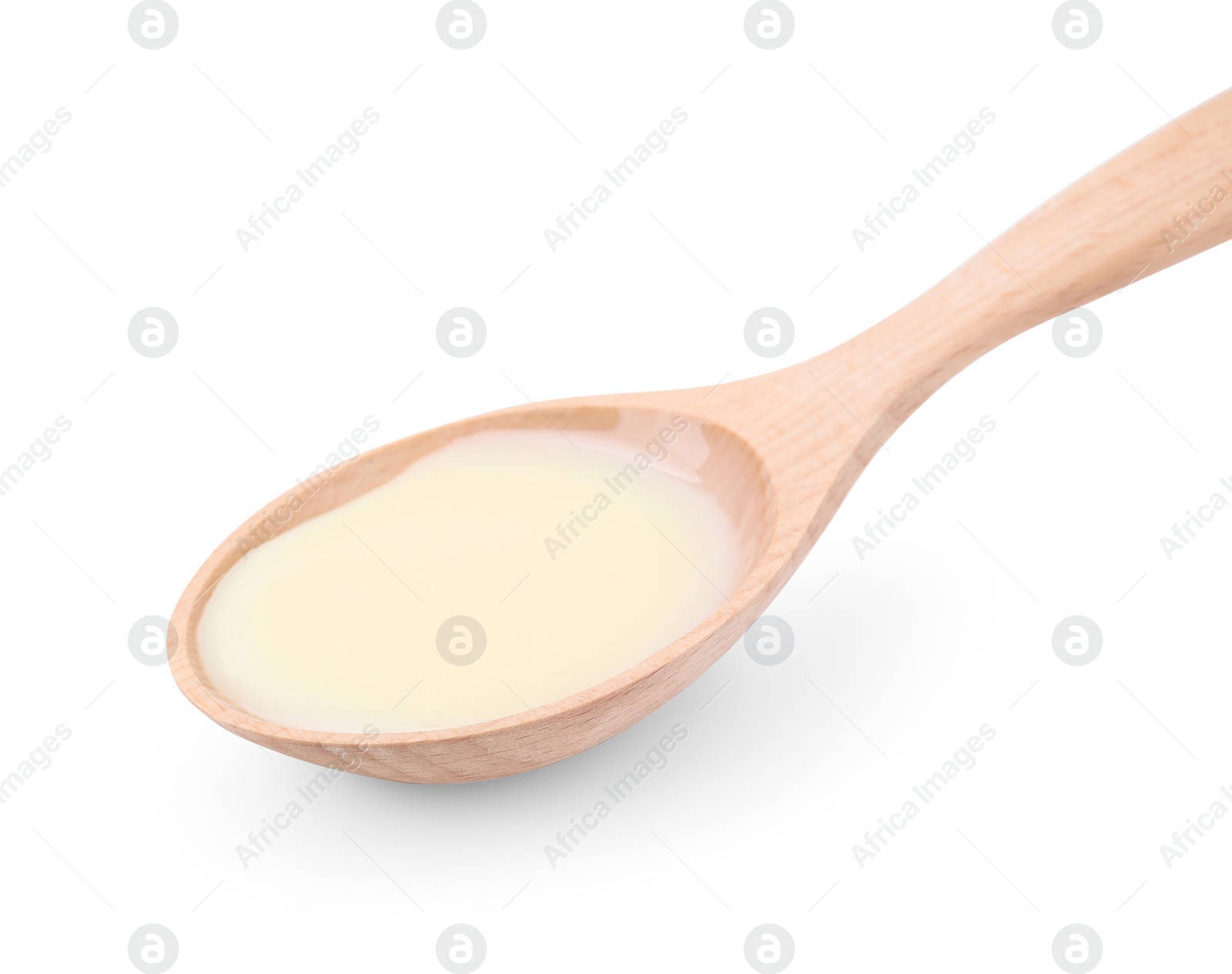 Photo of Wooden spoon with condensed milk isolated on white