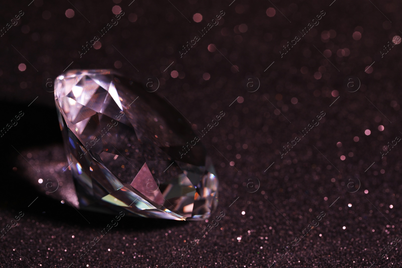 Photo of Beautiful dazzling diamond on black glitter surface, closeup. Space for text