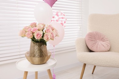 Photo of Beautiful roses on coffee table, comfortable armchair and air balloons in cozy room. Happy birthday