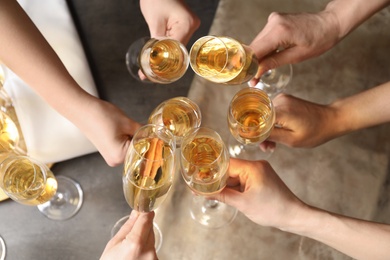 People clinking glasses with champagne over table, top view