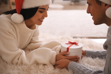 Photo of Couple holding Christmas gift box indoors, closeup