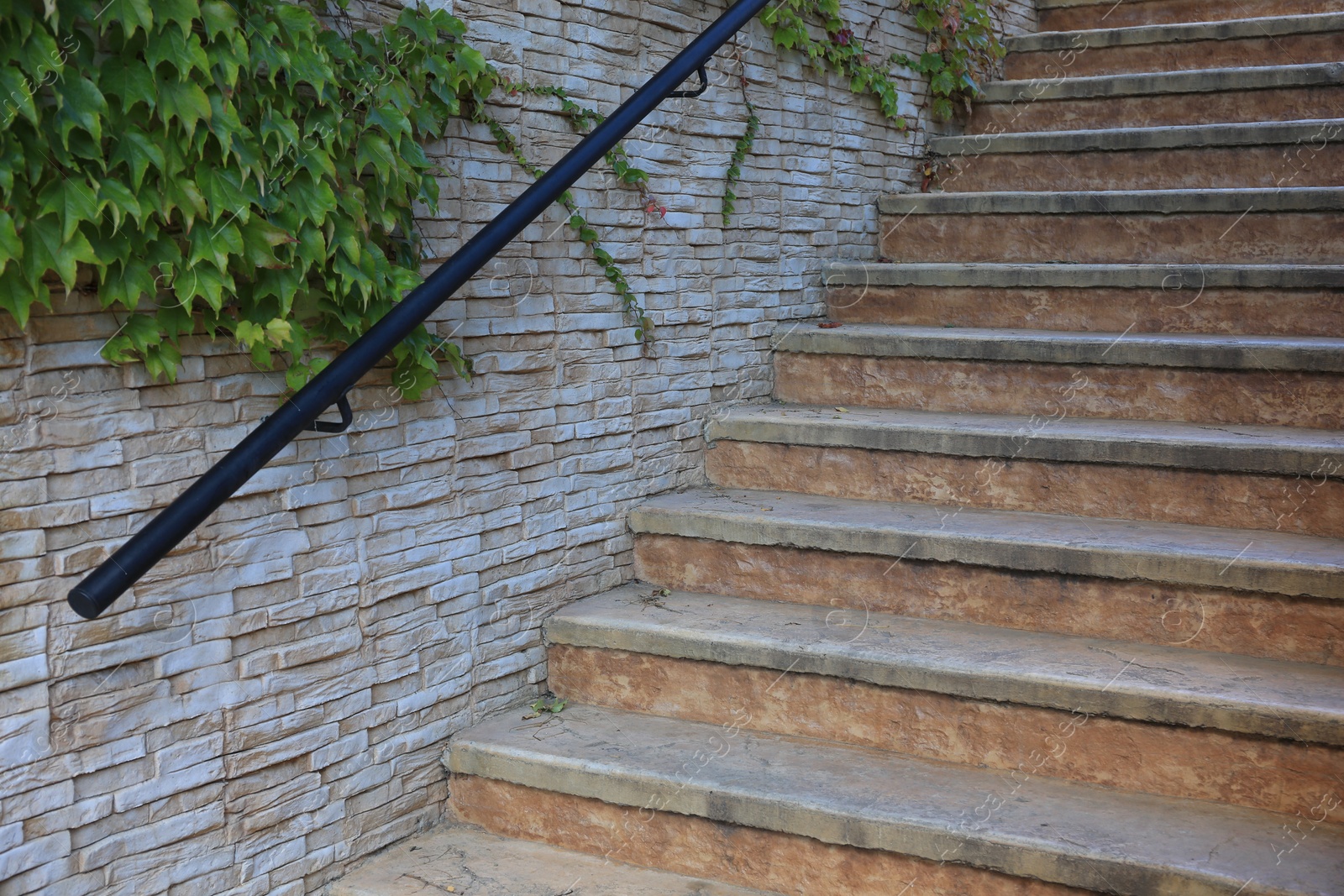 Photo of View of beautiful old stairs near brick wall with climber plant outdoors