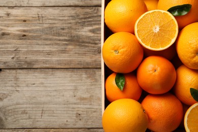 Photo of Many whole and cut ripe oranges on wooden table, top view. Space for text