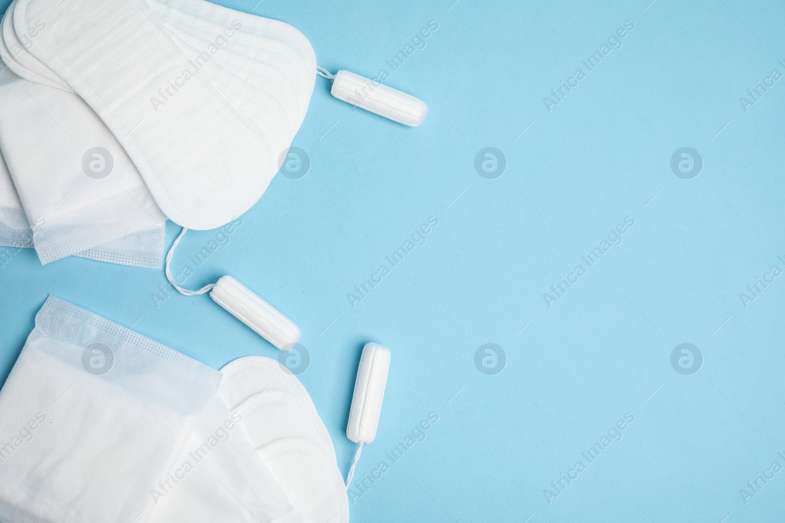 Photo of Menstrual pads, tampons and pantyliners on light blue background, flat lay. Space for text