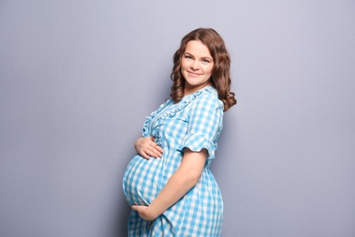 Photo of Young pregnant woman in casual clothes on grey background