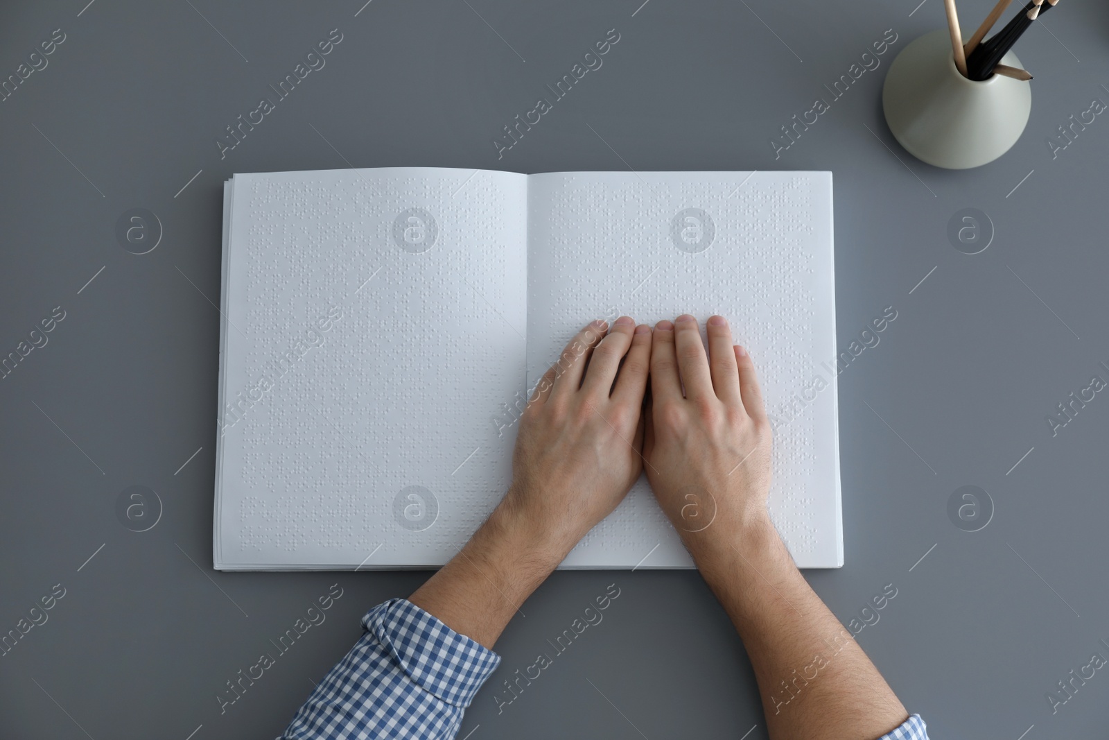 Photo of Blind man reading book written in Braille at table, top view