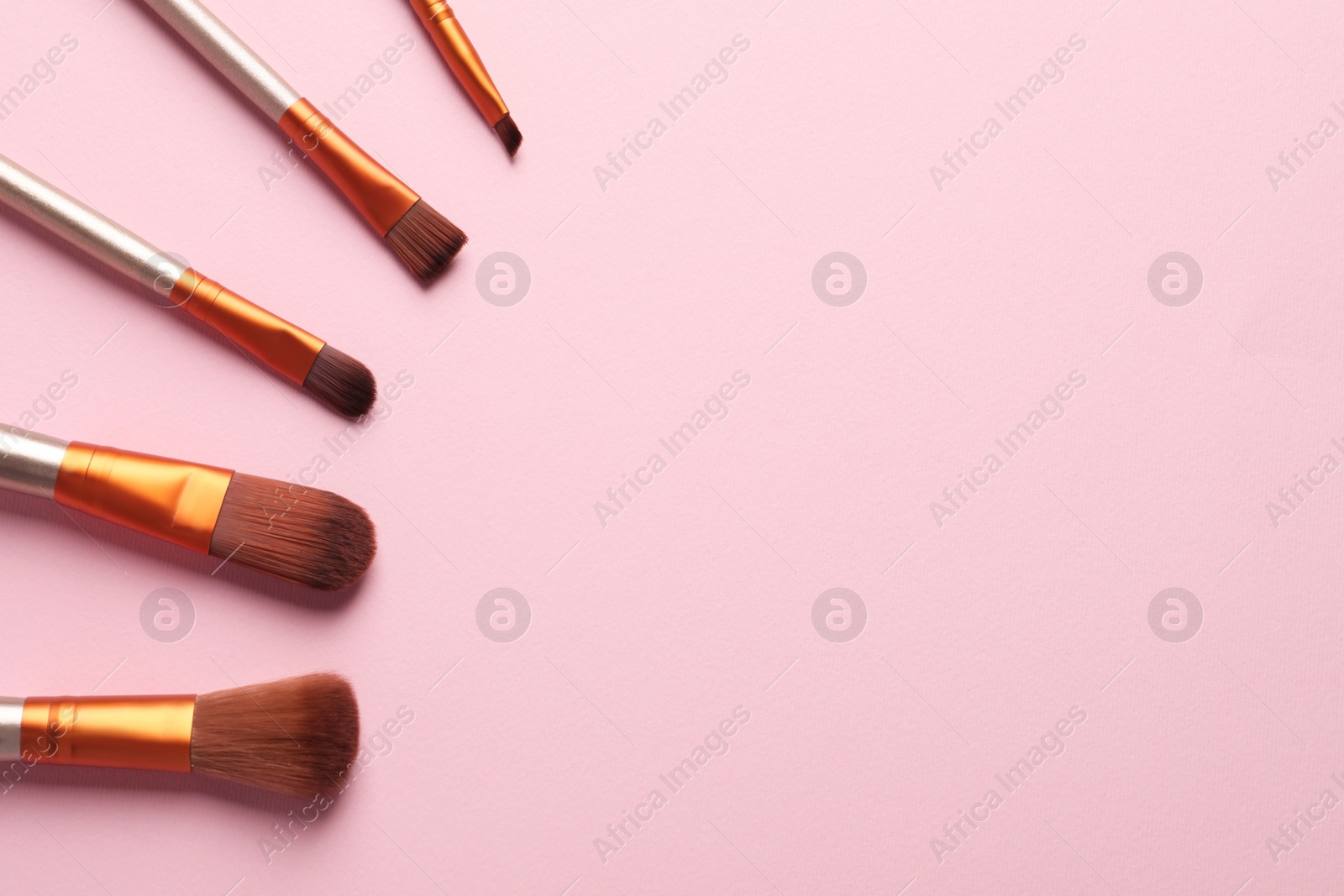 Photo of Set of makeup brushes on pink background, flat lay. Space for text