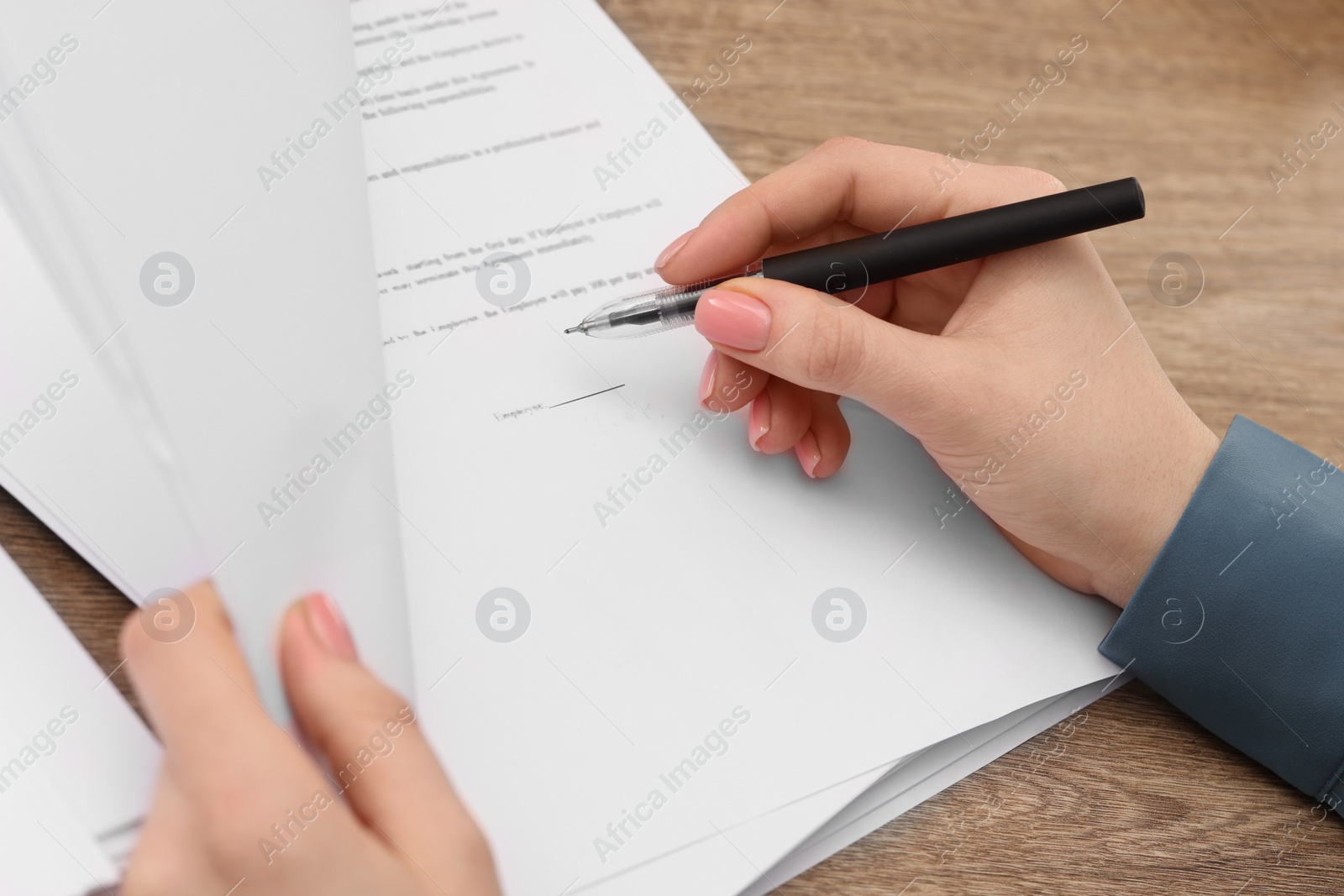 Photo of Woman signing document at wooden table, above view