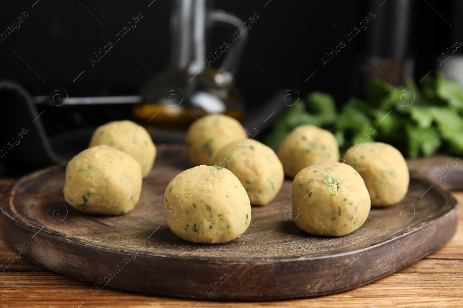 Photo of Wooden board with raw falafel balls on table, closeup