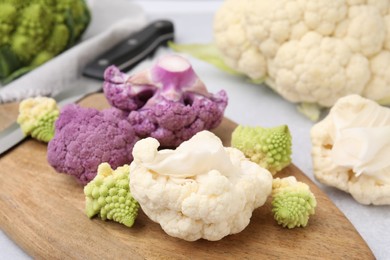 Photo of Various cauliflower cabbages on light grey table, closeup