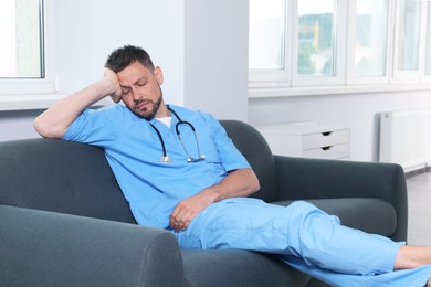 Photo of Exhausted doctor resting on sofa in hospital