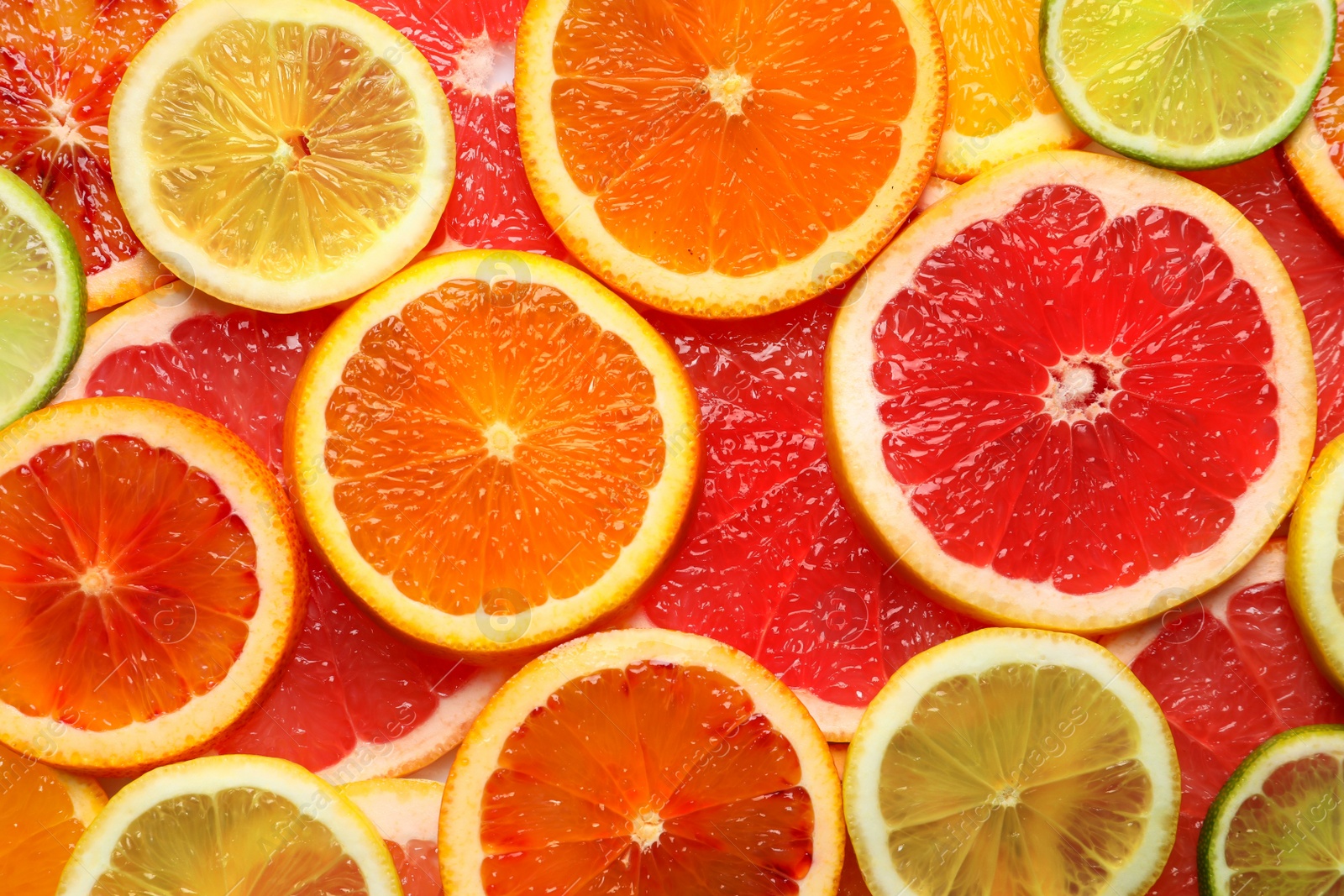 Photo of Slices of fresh citrus fruits as background, top view