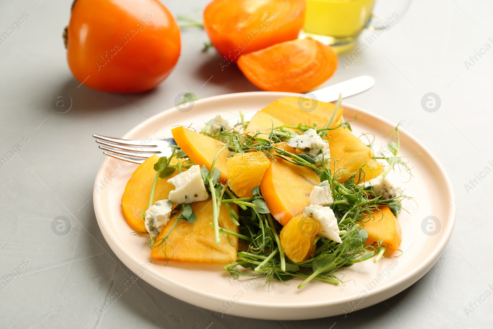 Photo of Delicious persimmon salad with blue cheese and orange on light grey table