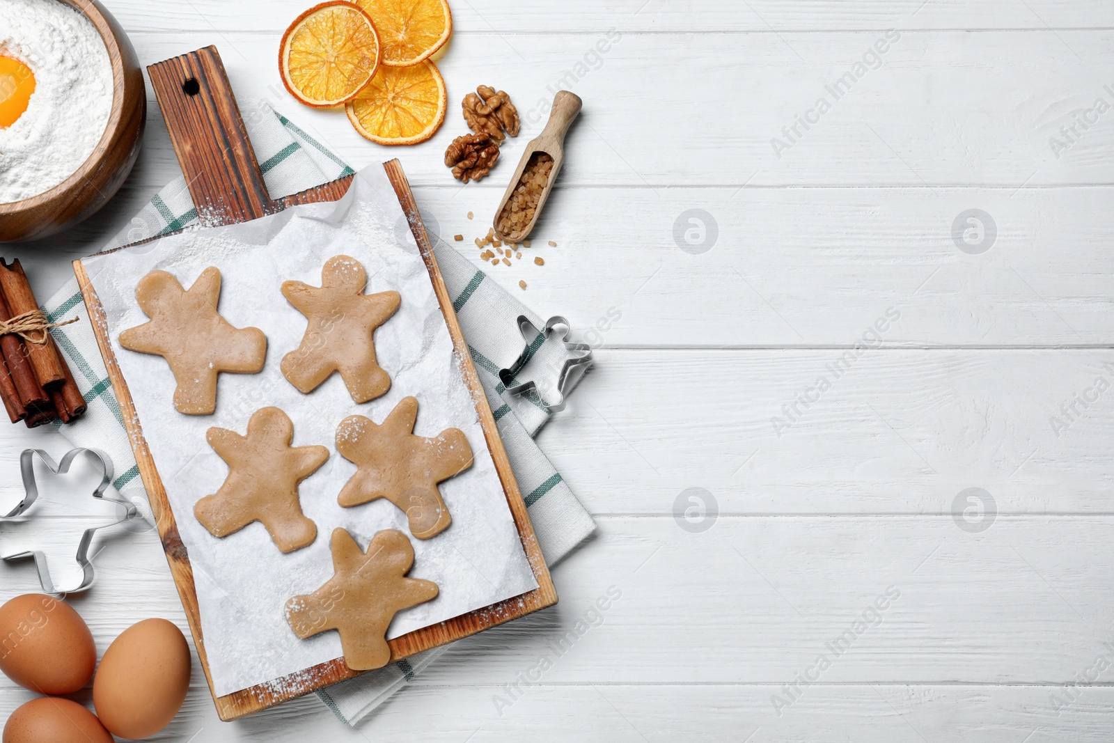Photo of Flat lay composition with homemade gingerbread man cookies on white wooden table, space for text