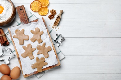 Flat lay composition with homemade gingerbread man cookies on white wooden table, space for text