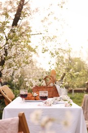 Stylish table setting with beautiful spring flowers, wine and croissants in garden