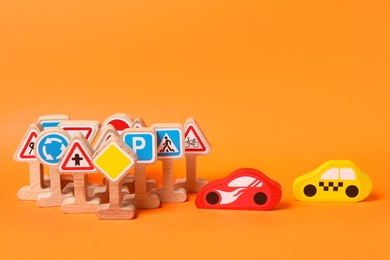 Photo of Set of wooden road signs and cars on orange background. Children's toy