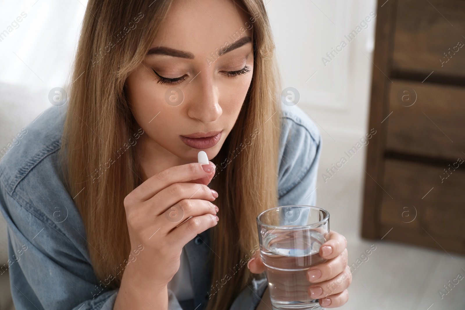 Photo of Young woman taking abortion pill at home