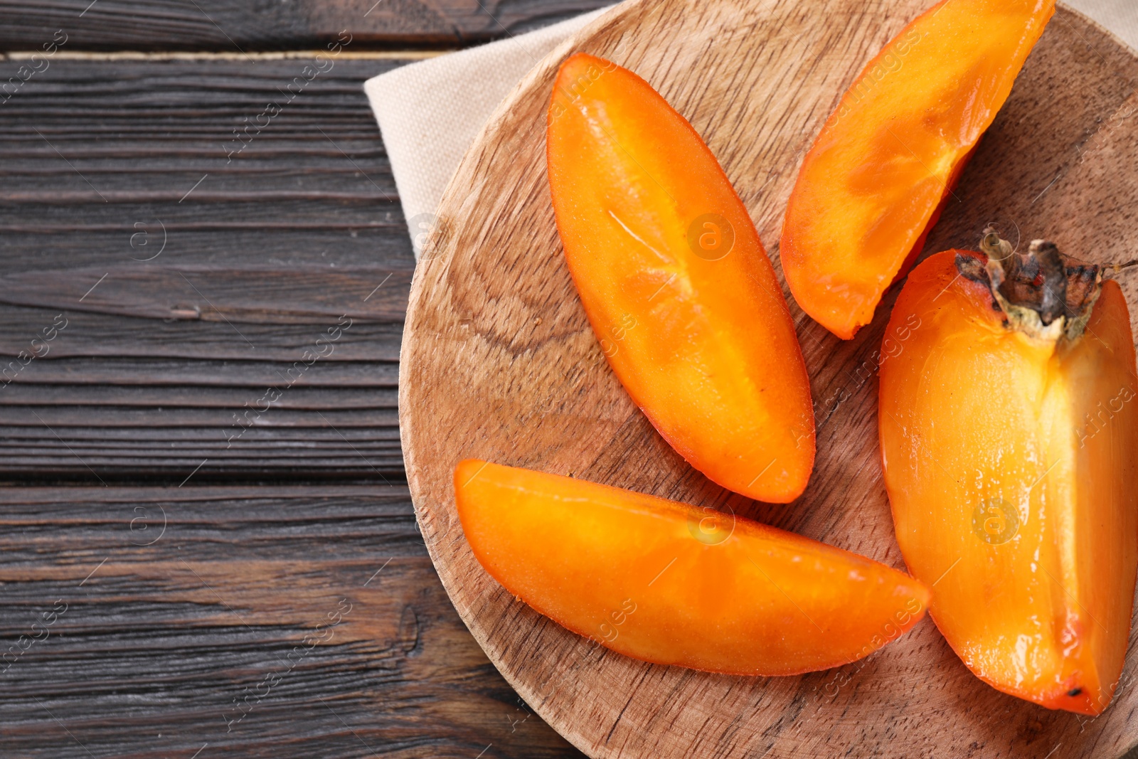 Photo of Pieces of delicious persimmons on wooden table, top view. Space for text