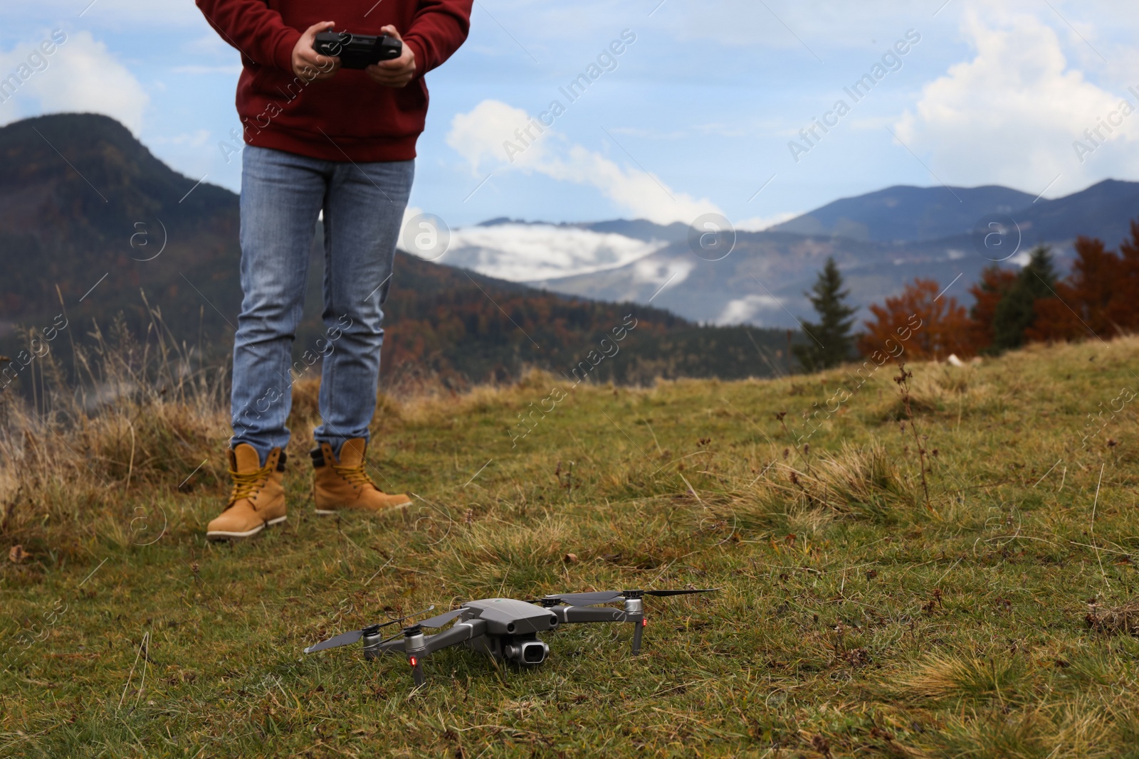 Photo of Man operating modern drone with remote control in mountains. Space for text