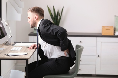 Businessman suffering from back pain at workplace