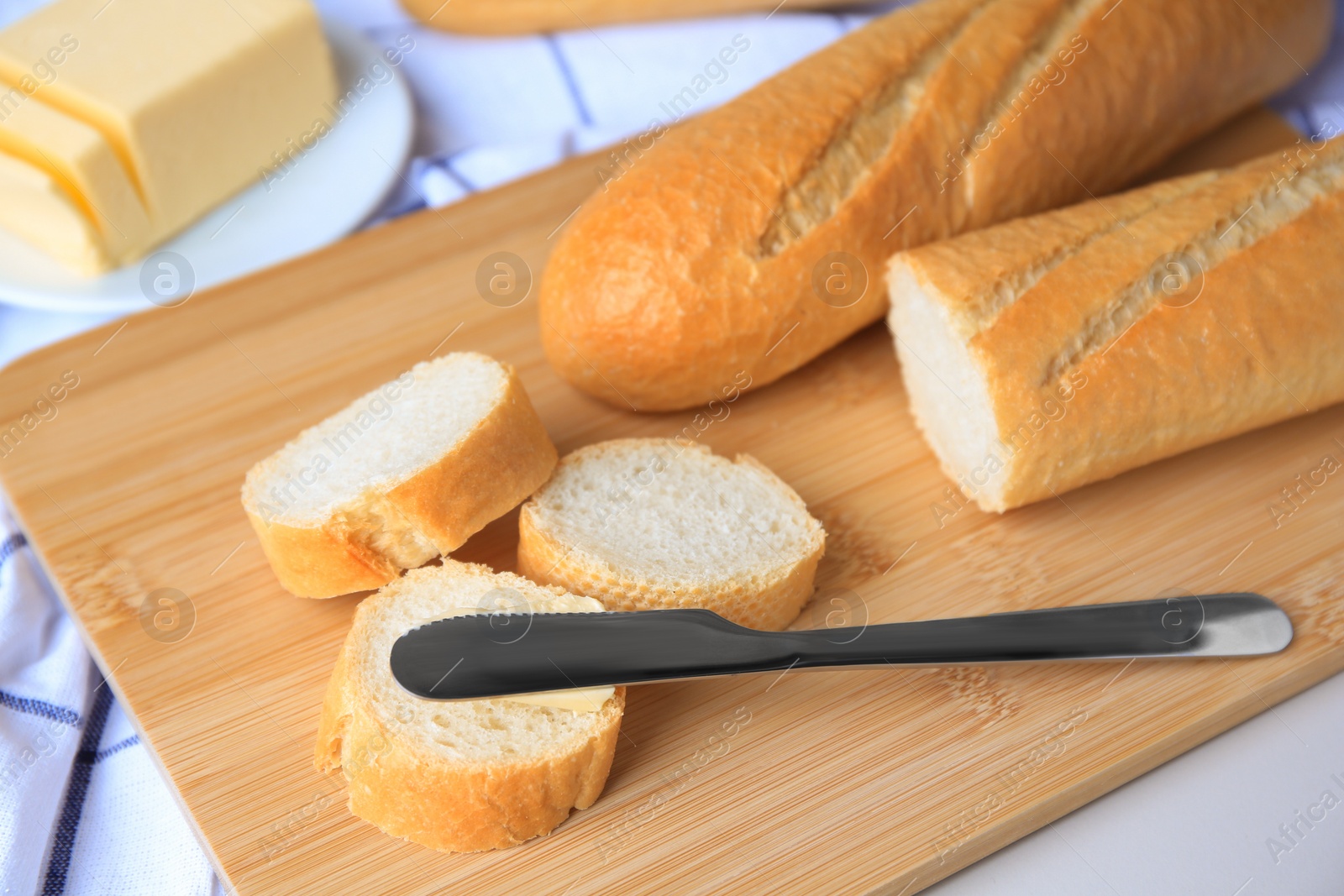 Photo of Tasty cut baguette with fresh butter on white table