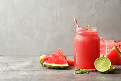 Photo of Summer watermelon drink in mason jar and sliced fruits on table against gray background with space for text